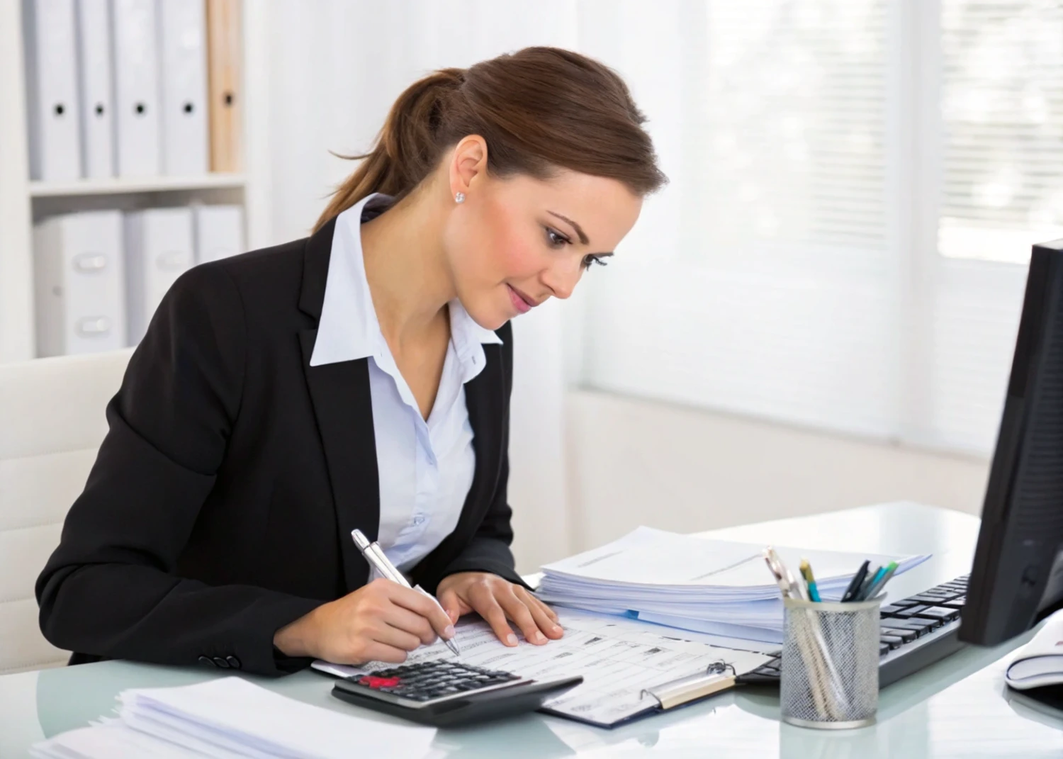 Accountant in Melbourne, Australia, working on financial documents and calculations at her desk